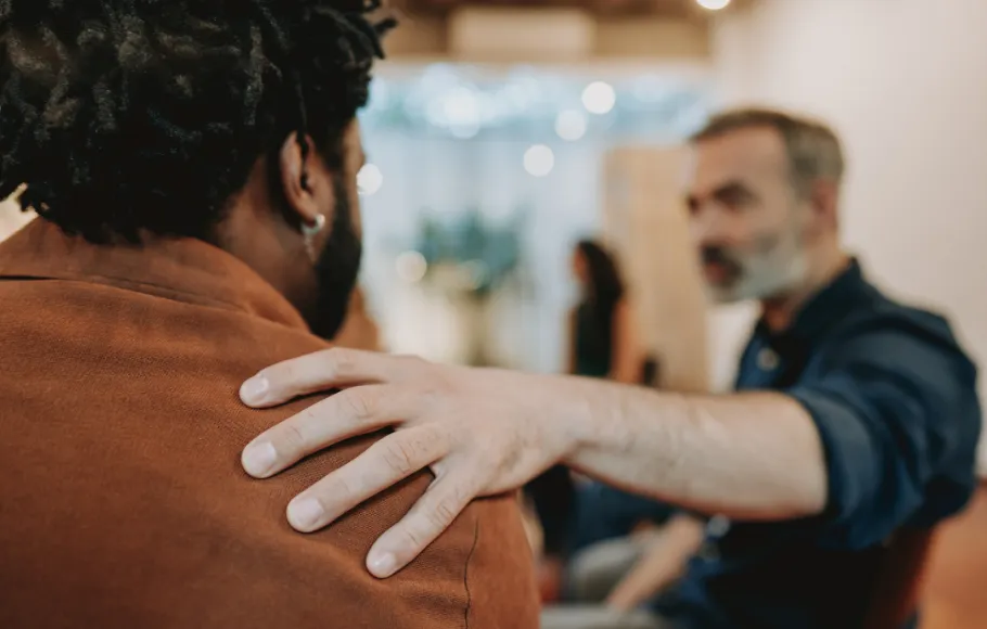 Mans hand på en annan mans axel