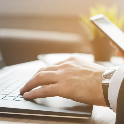 Man som skriver på datorn och mobilen